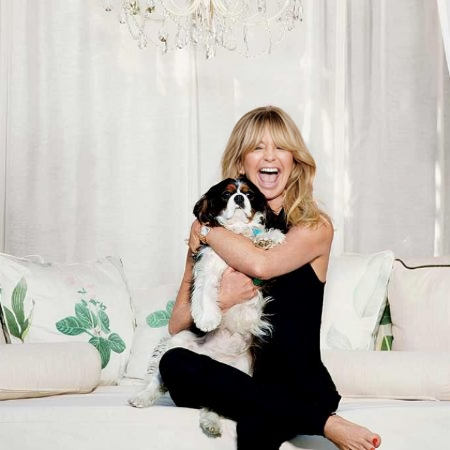 Goldie Hawn carrying dog sitting in a sofa.